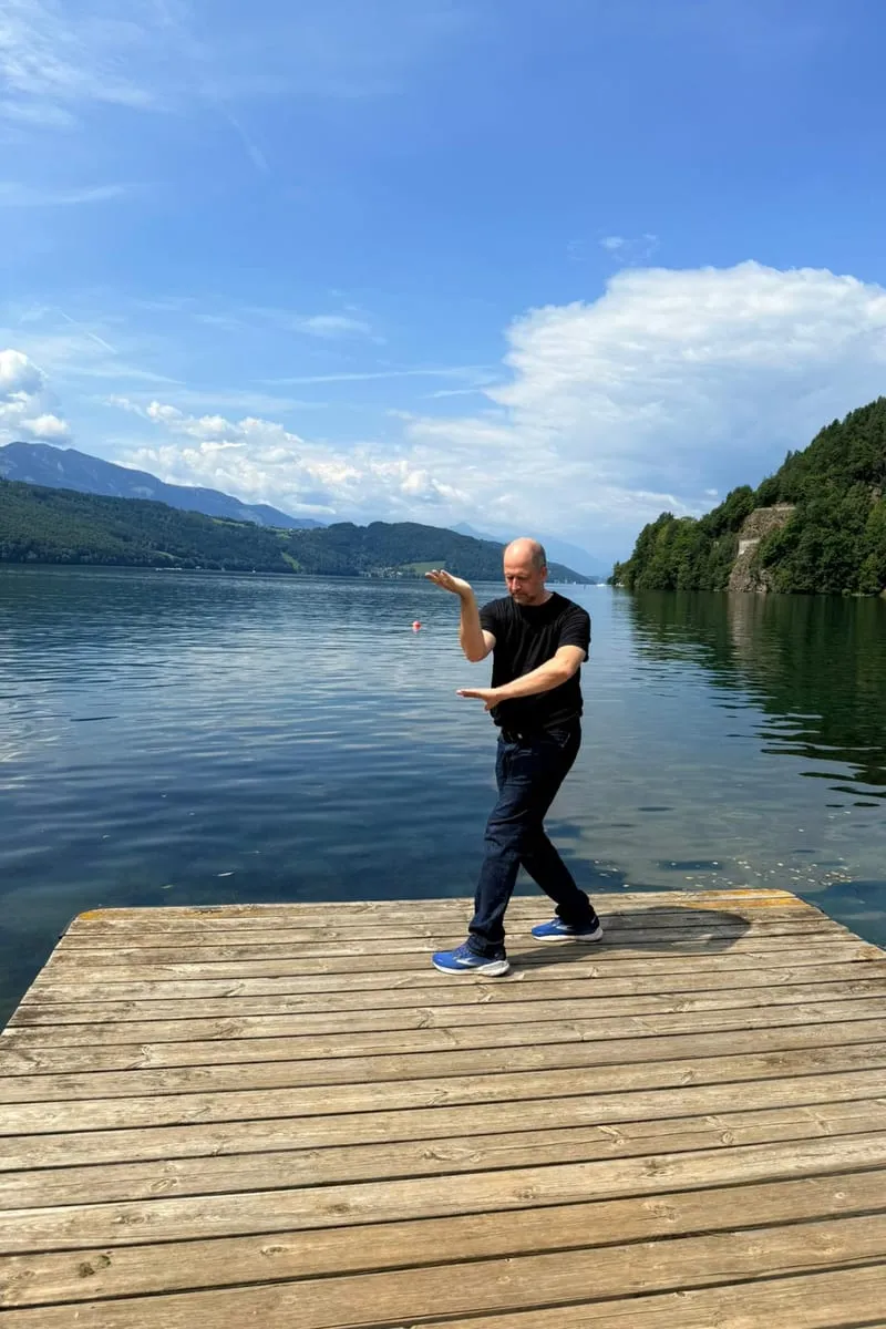 Wuji-Quan-Bewegung auf einem Steg am See — fließende Praxis in der Natur